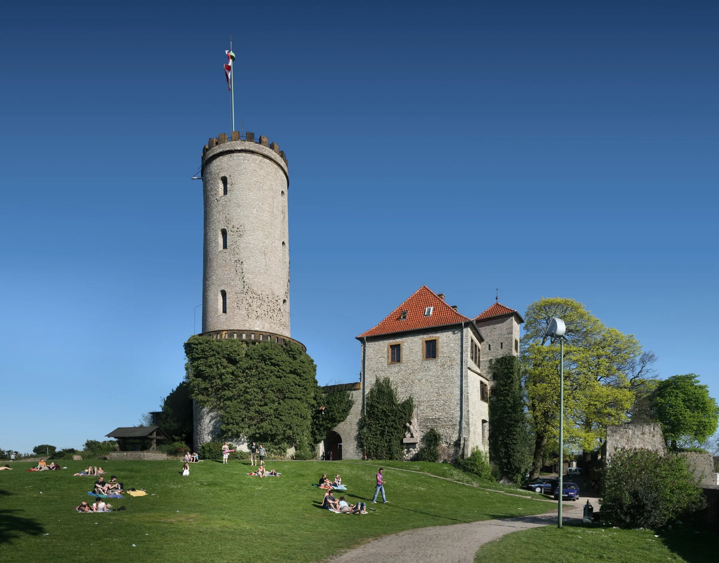 Die Sparrenburg in Bielefeld bei Sonnenschein, Menschen auf der Wiese davor