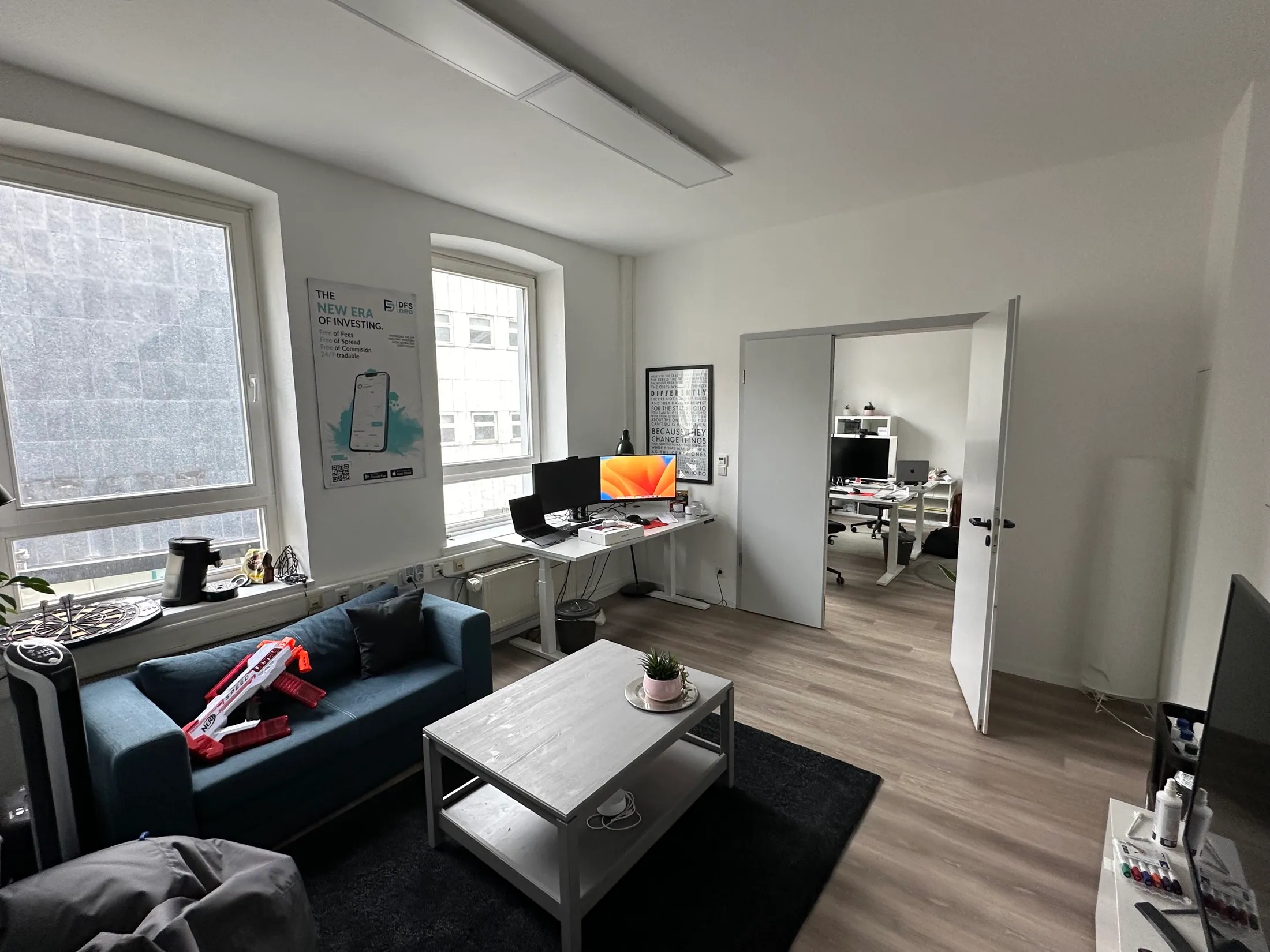 Lounge-Bereich des Büros mit blauem Sofa und Blick in den zweiten Arbeitsraum