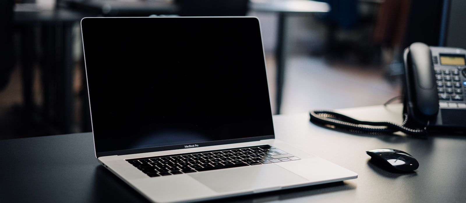 Aufgeräumter Schreibtisch mit Laptop und Telefon — ein kurzes Gespräch genügt, den Rest bauen wir.